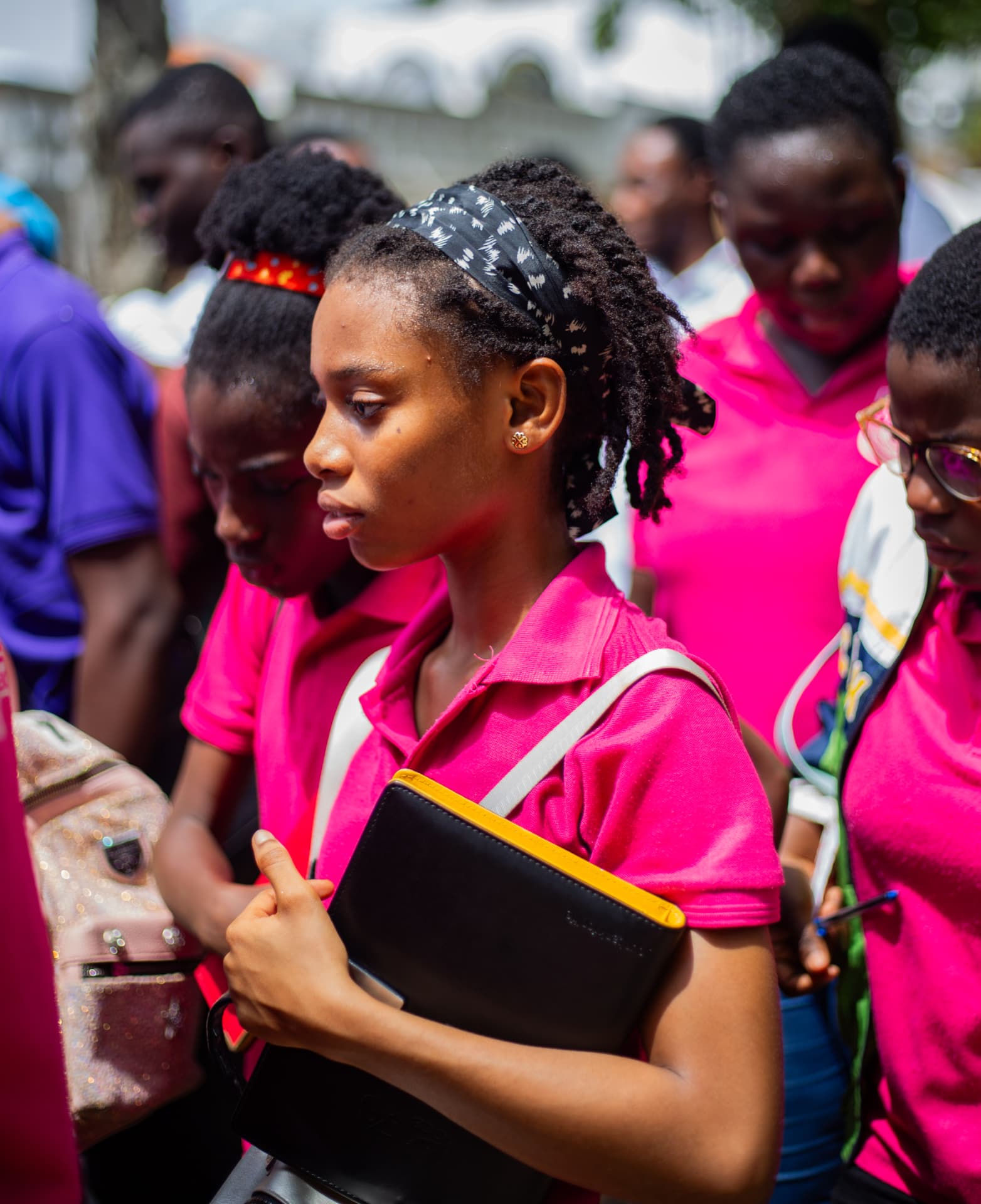 A Junior High learner in the school's pink uniform holding her folder